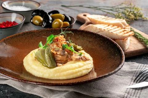 Mashed potatoes with beef stew in sauce, pickles and fried onions. Meat dish  Foto stock