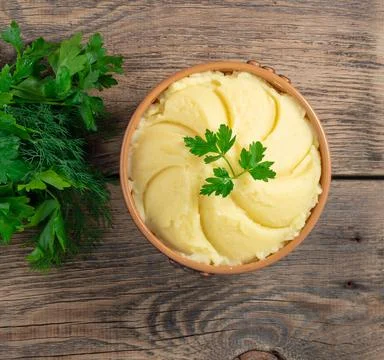 Mashed potatoes, boiled puree in brown bowl on dark wooden rustic background Stock Photos