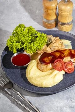 Mashed potatoes with chicken breast in red sauce with lettuce and tomato slic Foto stock
