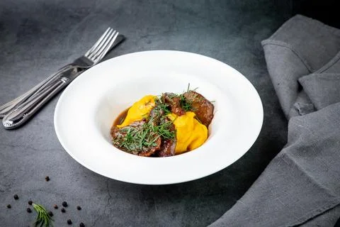 Mashed potatoes with meat, sauce and herbs in a deep plate side view Stock Photos