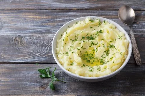 Mashed potatoes with melted butter and herbs in a gray ceramic bowl on a wooden Stock Photos