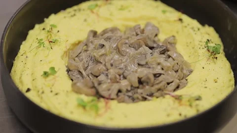 Mashed potatoes with mushrooms in the center of the dish and herbs Stock Footage 339383106