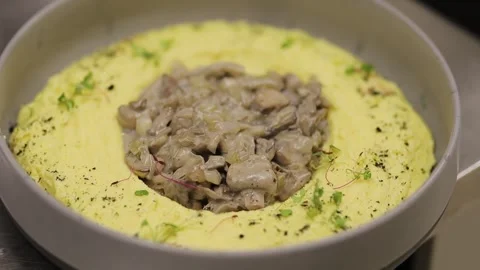 Mashed potatoes with mushrooms in the center of the dish and herbs Stock Footage 339383119