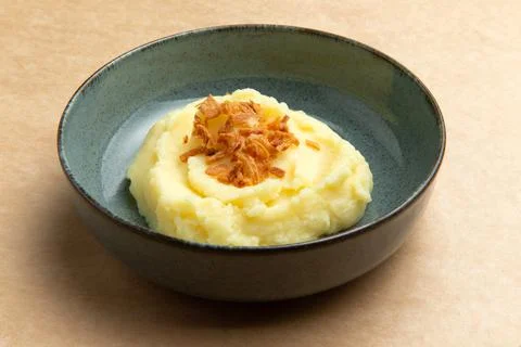 Mashed potatoes in a plate on a brown background. Stock Photos