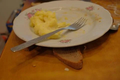 Mashed potatoes on a plate next to a fork of unfinished products on a brown Stock Photos