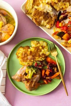 Mashed potatoes sit beside baked vegetables and stewed quail on green plates. Stock Photos