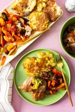 Mashed potatoes sit beside baked vegetables and stewed quail on green plates. Stock Photos