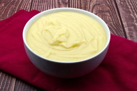 Mashed potatoes in white bowl on rustic table. Stock Photos