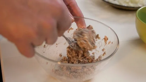 Mashing canned sardines using fork in glass bowl on white table slow motion Stock Footage 121364396