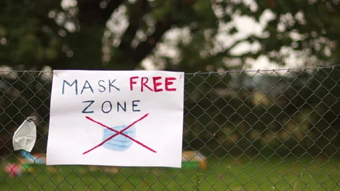 MASK DO NOT PROTECT AGAINST INFECTION. A poster on the fence with the Stock Footage 141464511