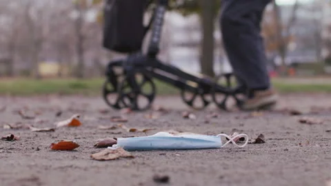 Mask laying on the ground, elderly walking by - Coronavirus Covid-19 Epidemic Stock Footage 165658655