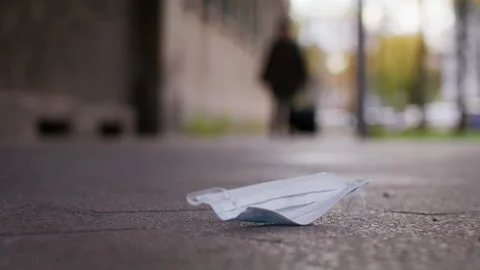 Mask laying on the ground, moves in wind - Coronavirus Covid-19 Epidemic Stock Footage 166033022