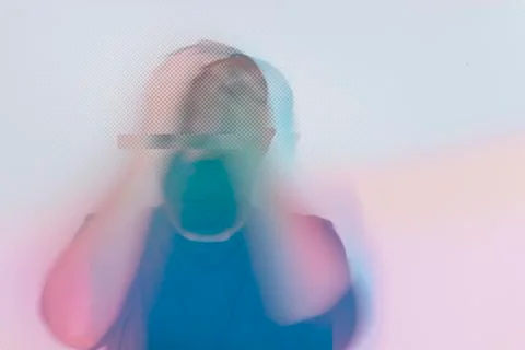 With a mask looking down, with his head in his hands. With a pastel edit Stock Photos