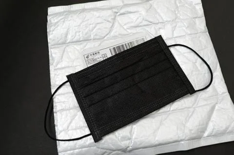Mask on top of bubble wrap padded envelope with China Post label. Stock Photos