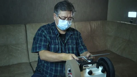 Masked asian man sharpens axe on a grinder Stock-Footage 143673561