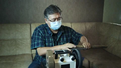 Masked asian man sharpens axe on a grinder Stock-Footage 143673613