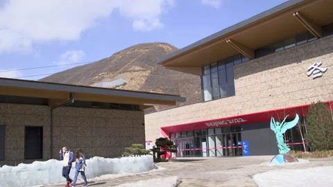 Masked athletes' and workers walking outside the Yanqing athletes' village Stock Footage 219767134