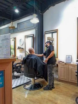Masked Barber Serving Client in Modern Barbershop During Pandemic Era Stock Photos