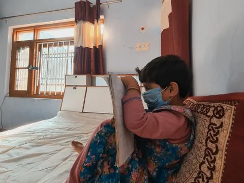 Masked Children doing school work read and writing at home during coronavirus Stock Photos