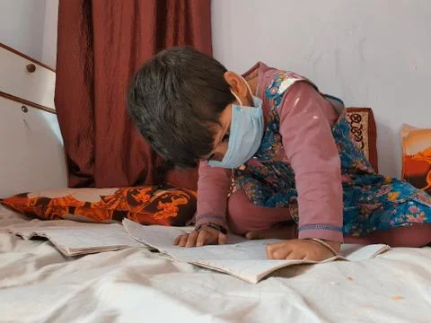 Masked Children doing school work read and writing at home during coronavirus Stock Photos