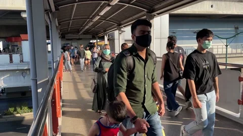 Masked commuters walking at Mo Chit BTS train station in the evening - POV Stock Footage 176841548