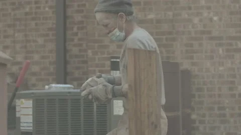 Masked construction worker walks over to lay more stone Stock Footage 144293987