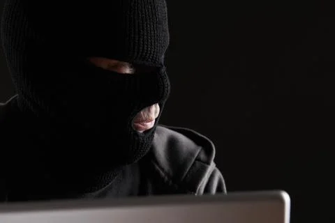 Masked Criminal Accessing Computer Data Foto stock