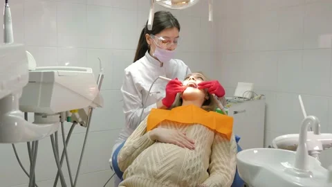 A masked dentist examines the teeth of a charming pregnant girl at a dentist Video stock 185183497