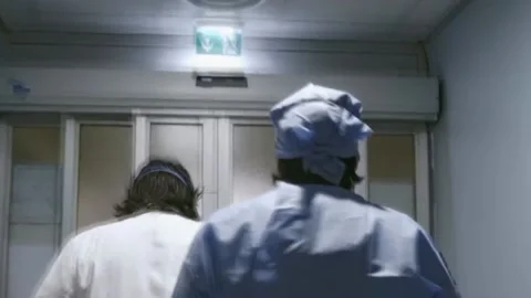 Masked doctors and protective suits walk along the hospital corridor Stock Footage 133380420