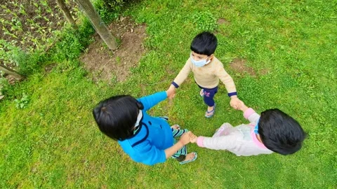 Masked girls playing ,swing, dancing circle, circling the child, enjoying and Stock Footage 220477447