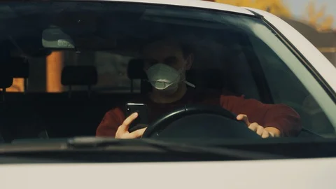 Masked guy makes a video call from a digital mobile while sitting in a car Stock Footage 129152516