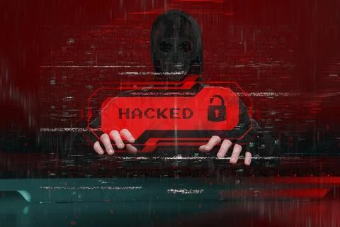 Masked hacker behind a computer with a red warning Hacked. Concept of cyber.. Stock Photos