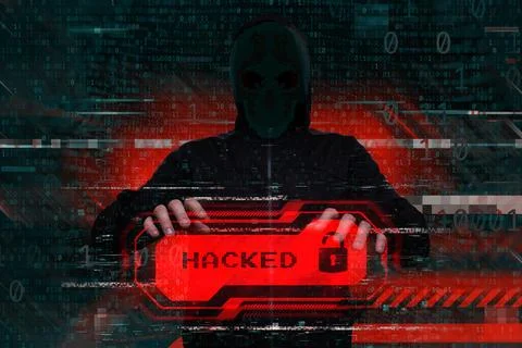 Masked hacker behind a computer with a red warning Hacked. Concept of cyber.. Stock Photos