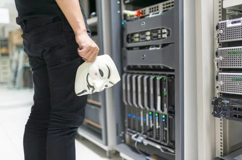 Masked Hacker in Computer Server room Concept Stock Photos
