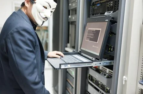 Masked Hacker in Computer Server room Concept Stock Photos
