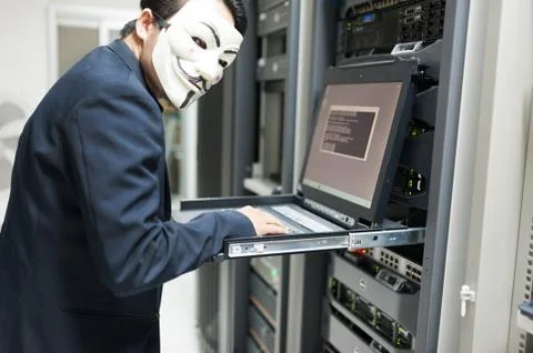 Masked Hacker in Computer Server room Concept Stock Photos