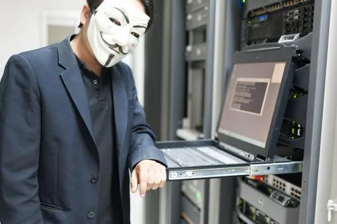 Masked Hacker in Computer Server room Concept Stock Photos