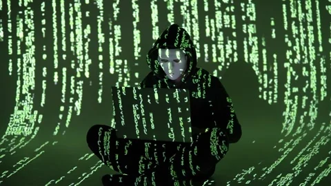 Masked Hacker in Digital Code Room Typing on Laptop in Dark Hoodie Surrounded Stock Footage 307177138