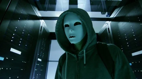 Masked Hacker in a Hoodie Walks Through Corporate Data Center Vídeo Stock 73938459