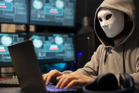 Masked hacker typing code and attempting data breach 스톡 사진