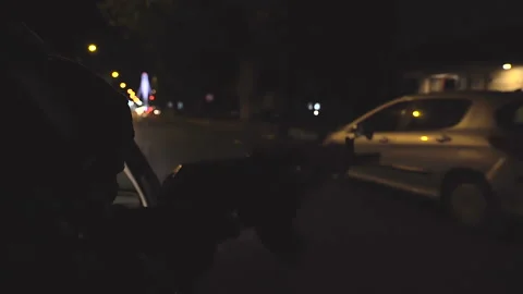 A masked killer throws a rifle out the car window at night Stock Footage 165499361