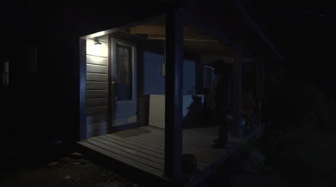 Masked killer walks walks toward log cabin holding knife in darkness. Stock Footage 44115233