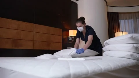 Masked maid in gloves making bed in hotel room Stock-Footage 148111463