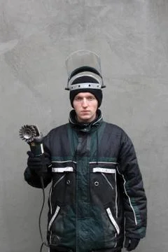 Masked man with grinder in hands. Worker in dirty clothes Foto stock