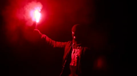 Masked Man Lights a Torch, and Lifts It Up Stock Footage 67669856