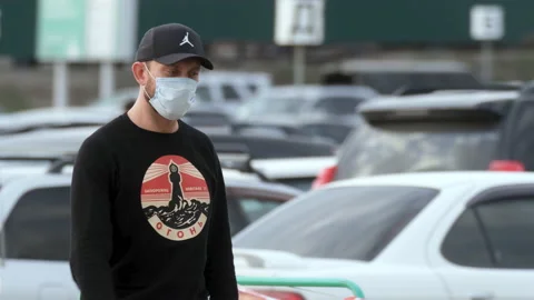 Masked man looking at camera walking parked corona virus. Human outdoor covid-19 Stock Footage 130742879