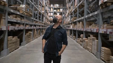 The masked man is looking at the store full of huge shelves. Search in disassemb Vídeo Stock 142026552