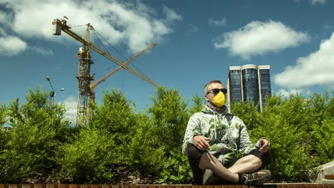 Masked man meditates on the background of construction cranes.Time lapse. Stock Footage 133225478