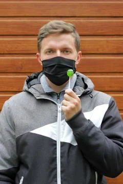 Masked man. Quarantine problem. A man cannot eat a lollipop. Discomfort due t Stock Photos