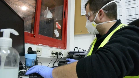 A masked man at a table works on a computer in office. Video stock 127191848